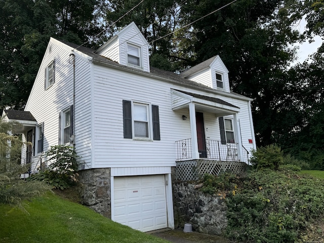 cape cod-style house featuring covered porch and a garage