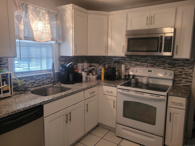 kitchen with white cabinets, light tile patterned floors, sink, stainless steel appliances, and decorative backsplash