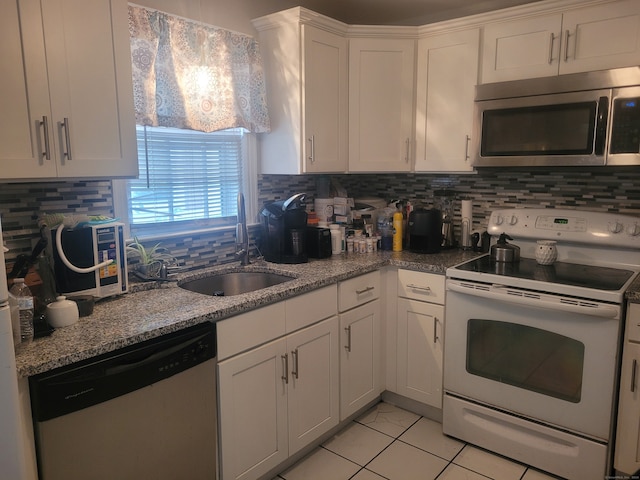 kitchen with light tile patterned flooring, tasteful backsplash, white cabinets, stainless steel appliances, and sink