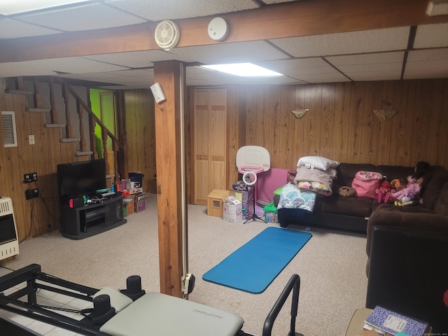 basement with wooden walls, a paneled ceiling, and carpet flooring