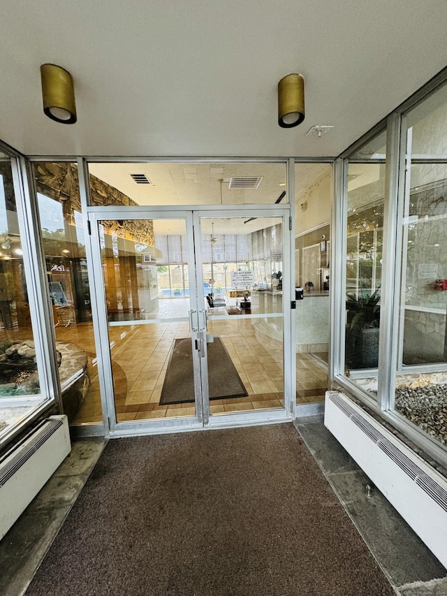 unfurnished sunroom featuring a baseboard heating unit, french doors, and visible vents