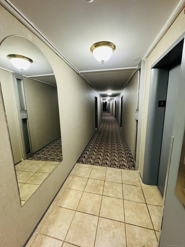 hall with arched walkways and tile patterned flooring