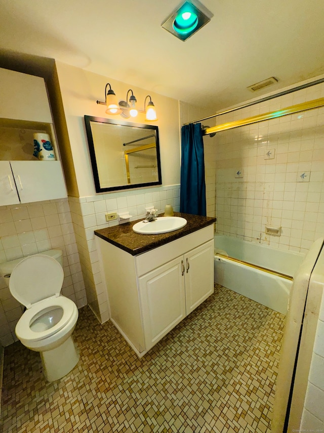 full bathroom featuring shower / bath combo with shower curtain, tile walls, vanity, and toilet