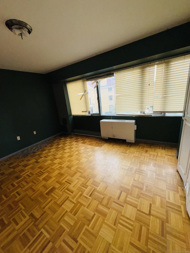spare room featuring radiator heating unit, baseboards, and a healthy amount of sunlight