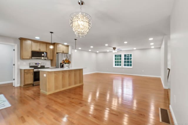 kitchen with a kitchen island, stainless steel appliances, ceiling fan with notable chandelier, light hardwood / wood-style floors, and decorative light fixtures