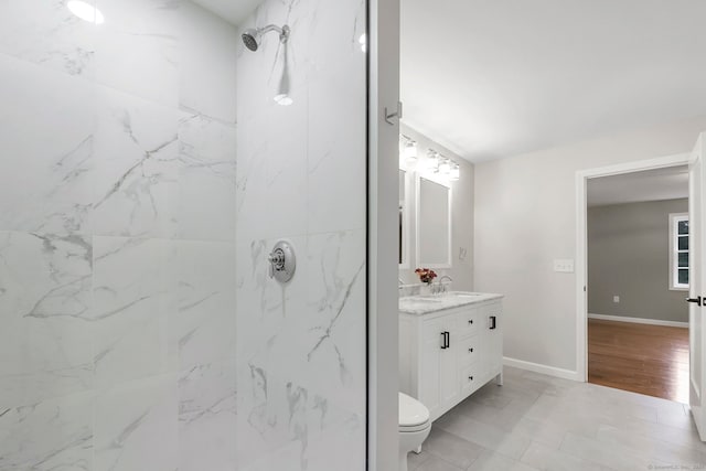 bathroom with vanity, toilet, wood-type flooring, and tiled shower