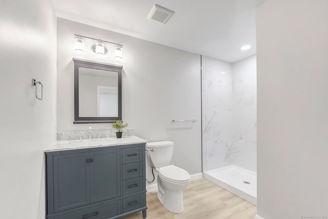 bathroom with vanity, tiled shower, hardwood / wood-style flooring, and toilet