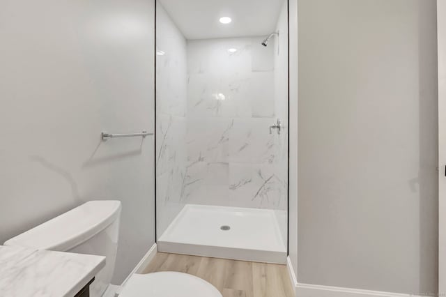 bathroom with vanity, tiled shower, wood-type flooring, and toilet