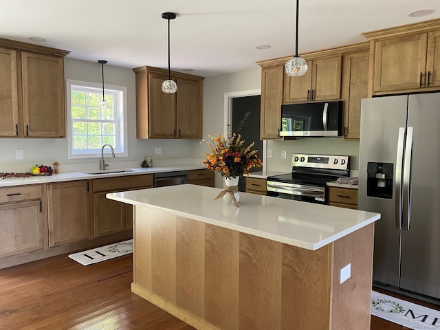 kitchen featuring a kitchen island, dark wood-type flooring, stainless steel appliances, sink, and pendant lighting