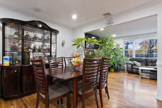 dining space featuring ornamental molding and hardwood / wood-style floors