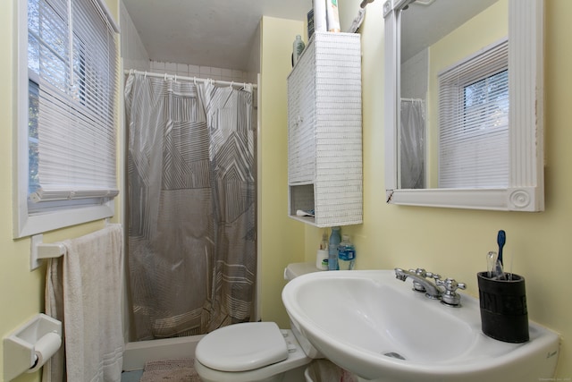 bathroom with toilet, walk in shower, and sink