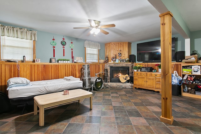 bedroom with a stone fireplace, ornate columns, and ceiling fan