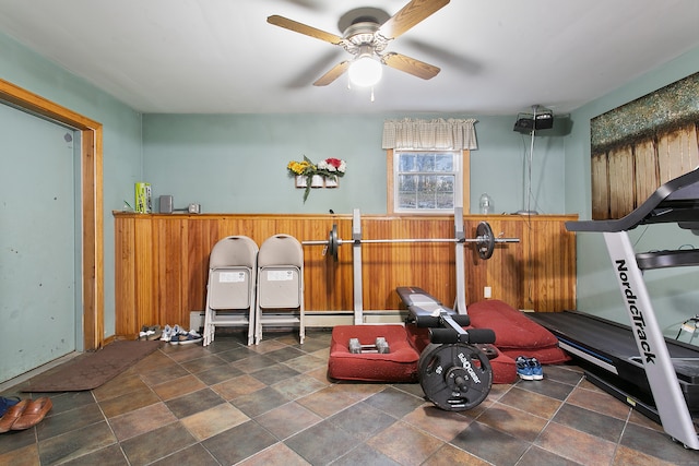 workout room featuring wood walls and ceiling fan