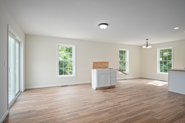 unfurnished living room featuring light hardwood / wood-style flooring and a notable chandelier