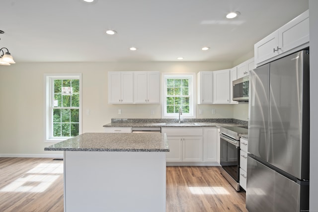 kitchen with white cabinets, appliances with stainless steel finishes, light hardwood / wood-style floors, and sink