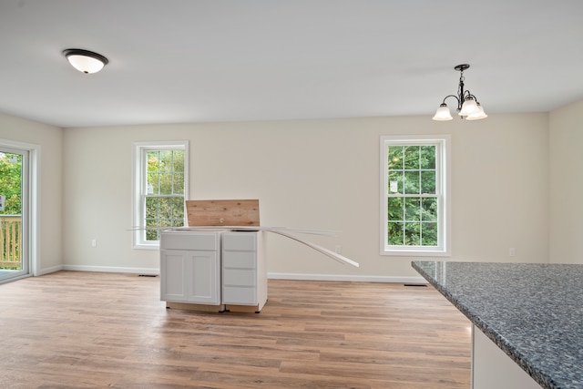 kitchen with white cabinetry, light wood-type flooring, a wealth of natural light, and pendant lighting