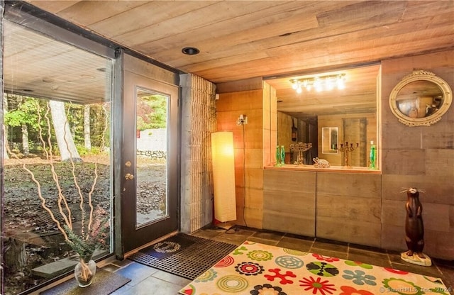 interior space with wood ceiling, wood walls, and tile patterned flooring