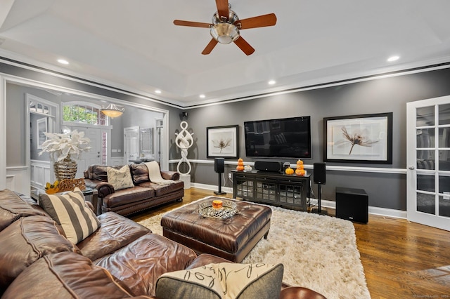 living room featuring ceiling fan, ornamental molding, a tray ceiling, and hardwood / wood-style floors