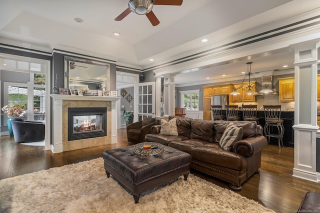 living room featuring dark hardwood / wood-style flooring, crown molding, a wealth of natural light, and decorative columns