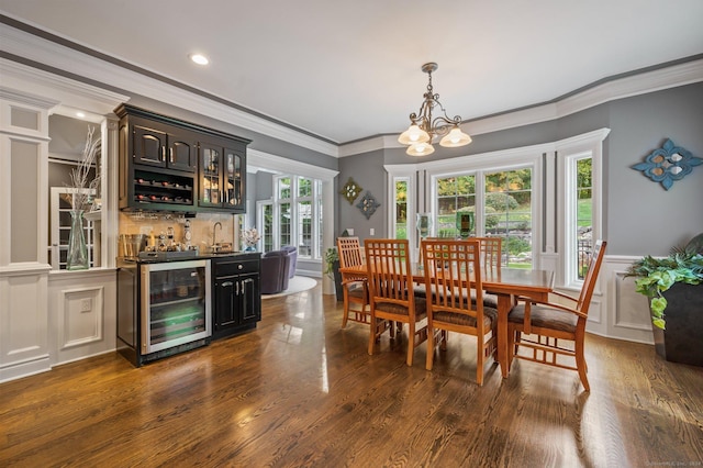 dining room with ornamental molding, dark hardwood / wood-style flooring, wet bar, beverage cooler, and a chandelier