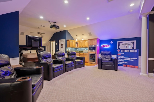 carpeted home theater with vaulted ceiling, decorative columns, sink, beverage cooler, and ceiling fan