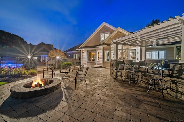 patio terrace at dusk featuring an outdoor fire pit, a pergola, and an outdoor bar