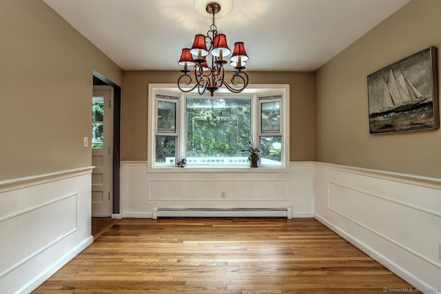 unfurnished dining area with an inviting chandelier, light wood-type flooring, a baseboard heating unit, and a wealth of natural light