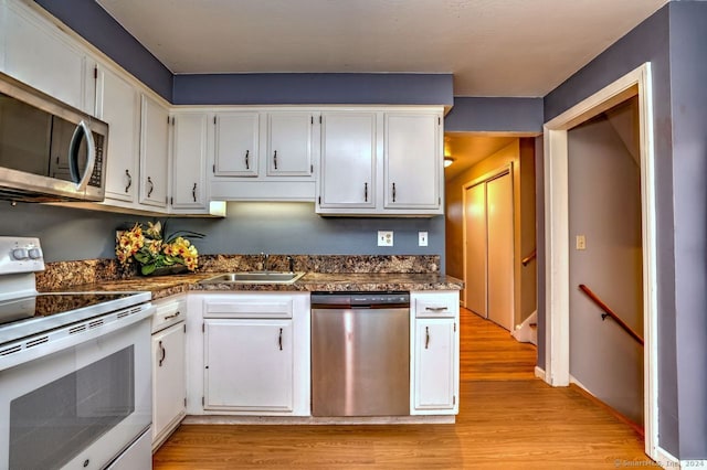 kitchen with white cabinets, appliances with stainless steel finishes, and light wood-type flooring