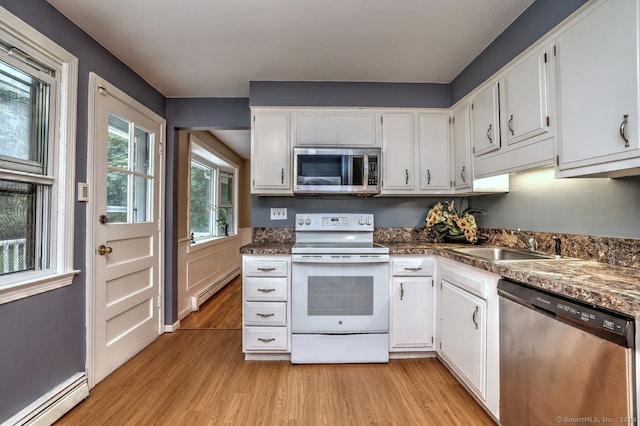 kitchen featuring appliances with stainless steel finishes, white cabinetry, a baseboard heating unit, and light hardwood / wood-style flooring