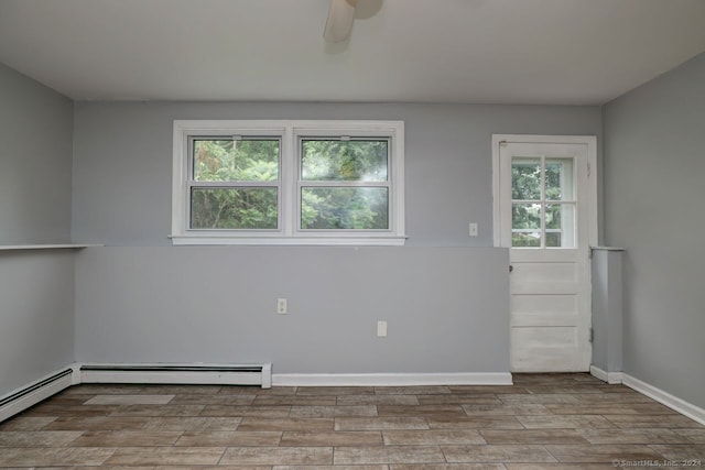 spare room featuring ceiling fan, a baseboard radiator, light hardwood / wood-style floors, and a wealth of natural light