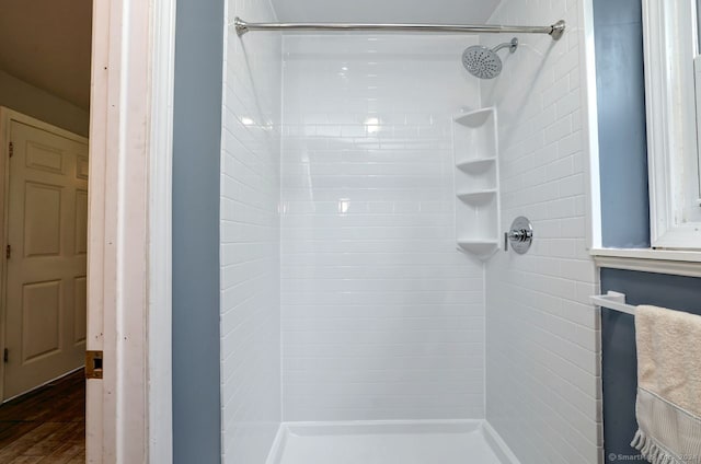 bathroom featuring wood-type flooring and a tile shower