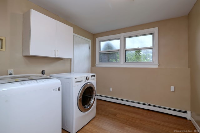 washroom with cabinets, light wood-type flooring, baseboard heating, and washer and clothes dryer