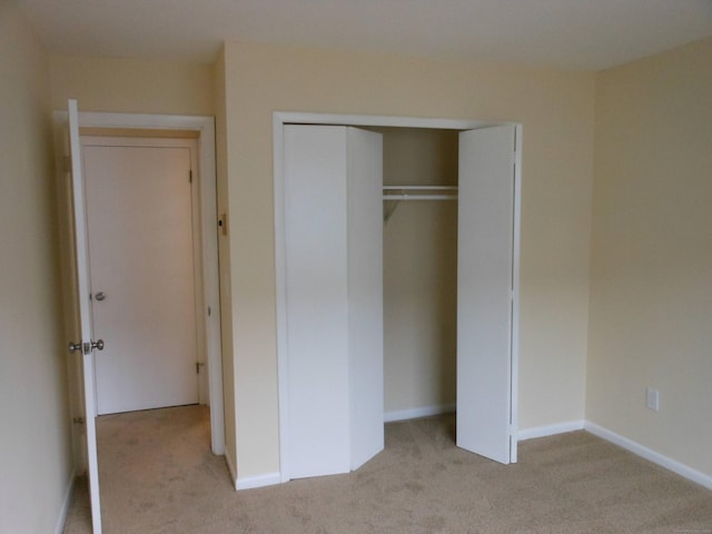 unfurnished bedroom with light colored carpet and a closet