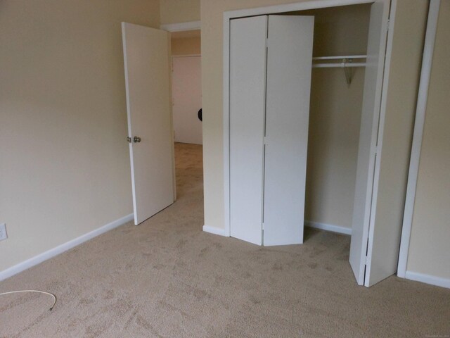 unfurnished bedroom featuring light carpet and a closet