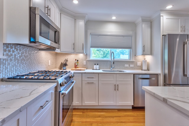 kitchen featuring sink, appliances with stainless steel finishes, white cabinetry, and tasteful backsplash