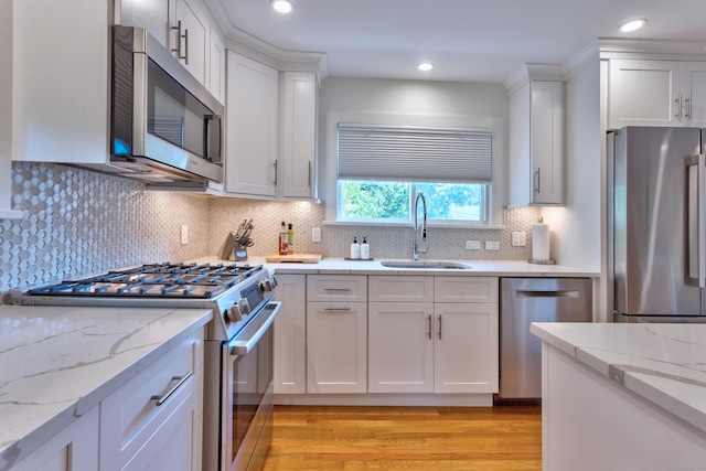 82 Thimble Island Rd, Branford, CT 06405 - kitchen with stainless steel appliances, light wood-style flooring, white cabinets, decorative backsplash, and recessed lighting