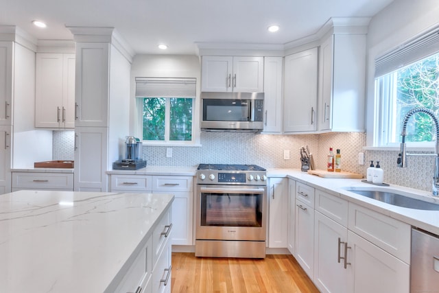 82 Thimble Island Rd, Branford, CT 06405 - kitchen featuring stainless steel appliances, white cabinetry, light wood-type flooring, backsplash, and recessed lighting