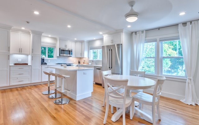 kitchen with appliances with stainless steel finishes, white cabinets, light wood-type flooring, and a wealth of natural light