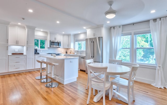 82 Thimble Island Rd, Branford, CT 06405 - kitchen with appliances with stainless steel finishes, a kitchen island, white cabinetry, backsplash, and recessed lighting