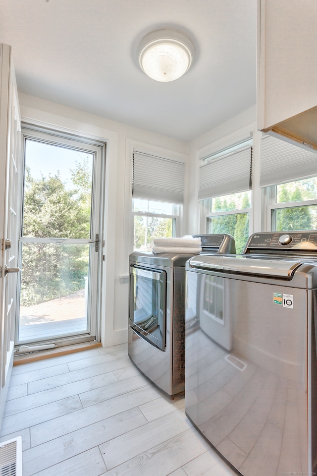 laundry area featuring a healthy amount of sunlight, light hardwood / wood-style flooring, and separate washer and dryer