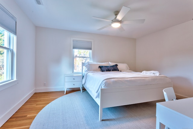 bedroom with multiple windows, wood-type flooring, and ceiling fan