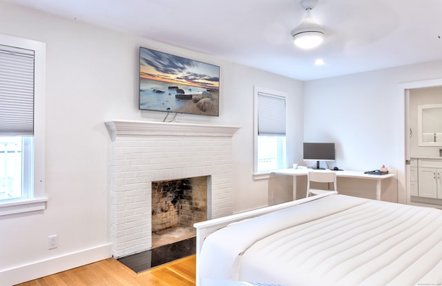 bedroom with wood-type flooring and a brick fireplace