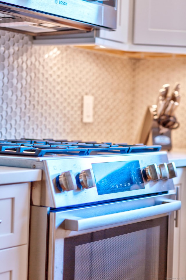 82 Thimble Island Rd, Branford, CT 06405 - kitchen view of gas stove, white cabinetry, light countertops, and tasteful backsplash