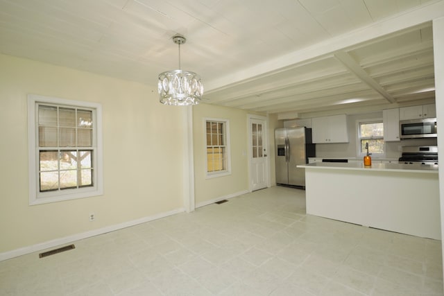 kitchen with appliances with stainless steel finishes, pendant lighting, a wealth of natural light, and white cabinetry