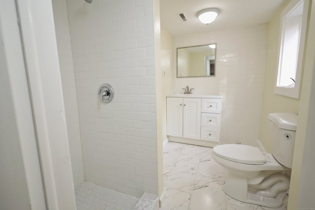 bathroom featuring vanity, tiled shower, and toilet