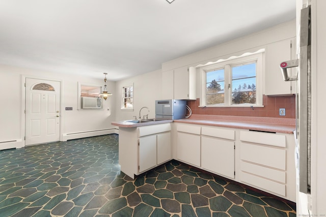 kitchen featuring sink, a baseboard radiator, white cabinets, and kitchen peninsula