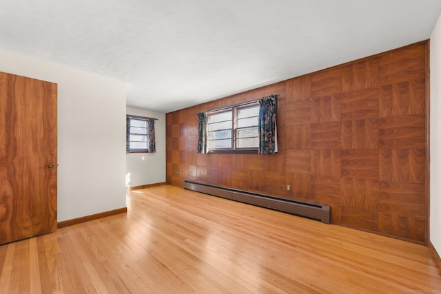 spare room with baseboard heating and light hardwood / wood-style flooring