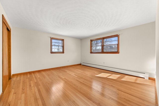 spare room with baseboard heating and light hardwood / wood-style floors