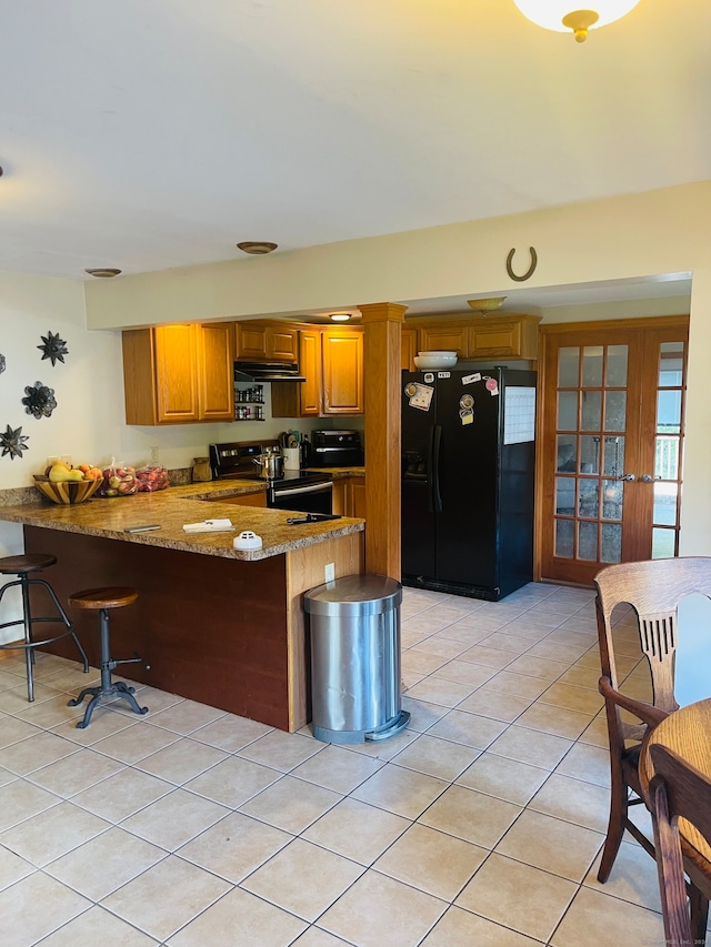 kitchen featuring light tile patterned floors, kitchen peninsula, stainless steel range with electric stovetop, black refrigerator with ice dispenser, and light stone countertops