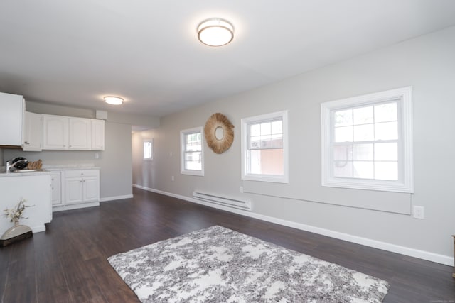 unfurnished living room featuring dark wood-type flooring and a baseboard heating unit